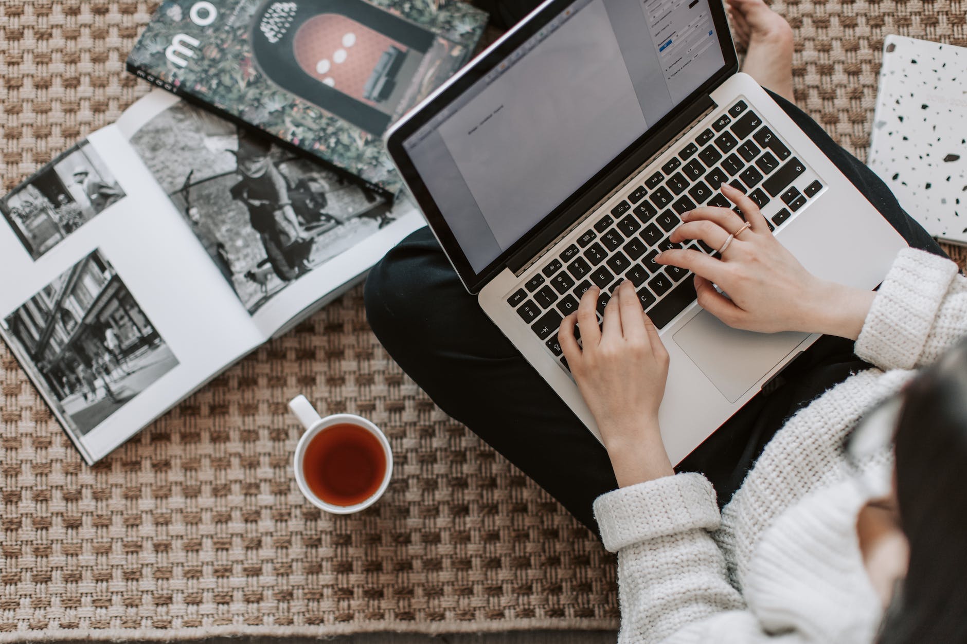 crop young businesswoman using laptop while drinking tea at home